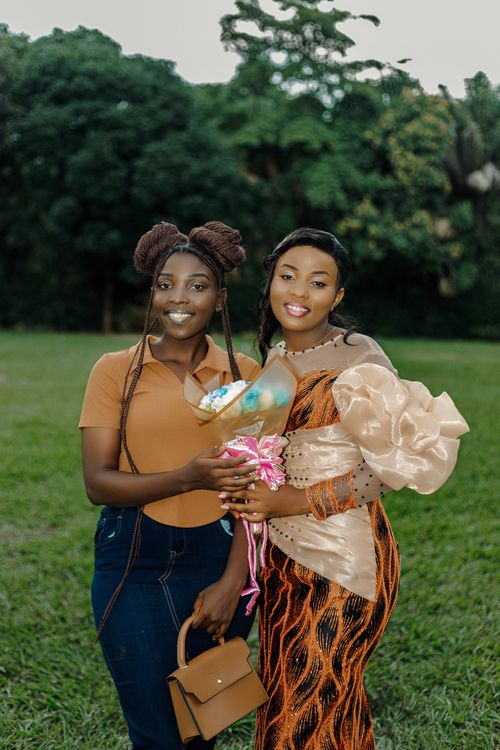 Free Two women standing together with smiles, holding a bouquet in a lush green garden. Stock Photo