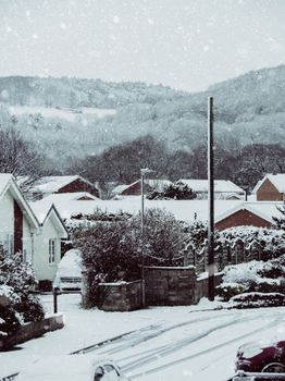 A peaceful village covered in snow during winter, with homes and hills in the background.
