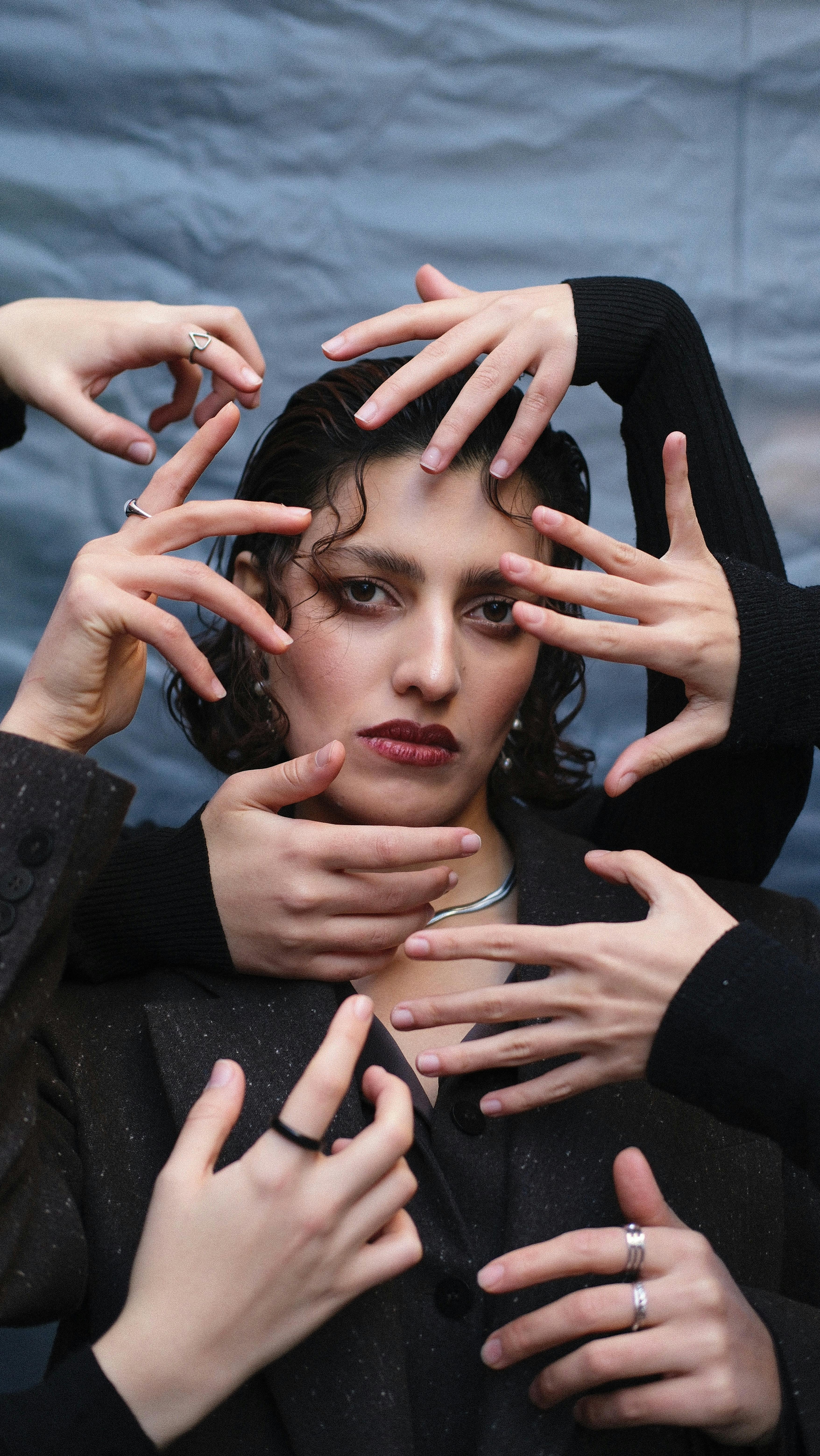 Creative portrait of a woman framed by multiple hands, conveying an artistic and dramatic mood.