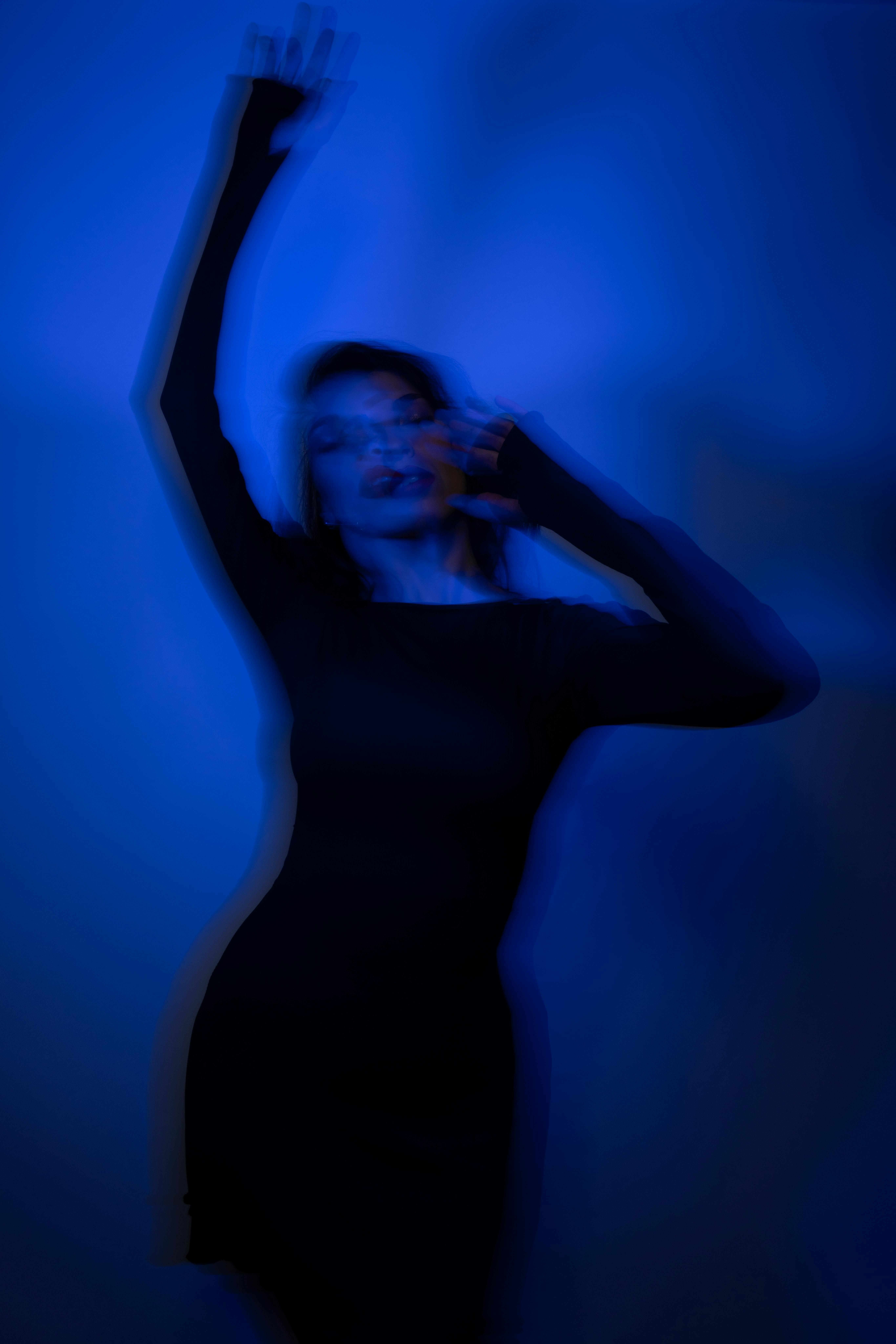 A blurred artistic portrait of a female model under dramatic blue lighting, creating a moody aesthetic.