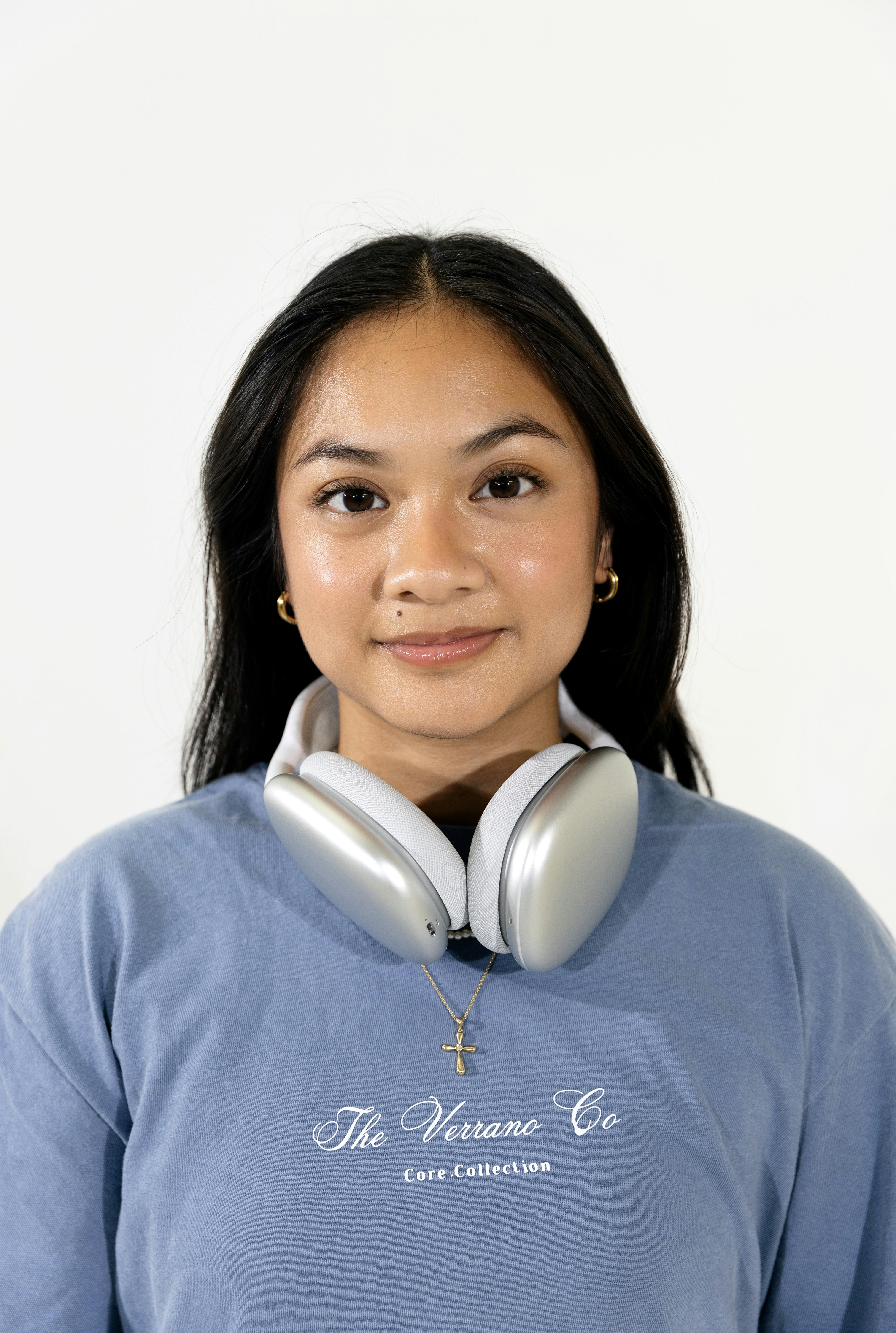 Free Portrait of a young woman wearing headphones and a casual t-shirt, looking confidently at the camera. Stock Photo