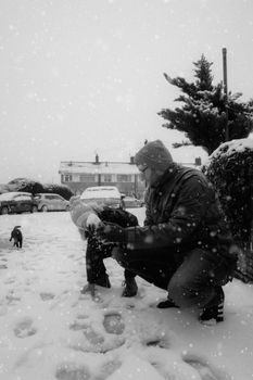 Father and son bonding while playing in a snowy neighborhood, capturing winter fun.