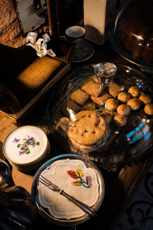 Free Delicious assortment of cookies and elegant plates in warm, cozy setting. Stock Photo
