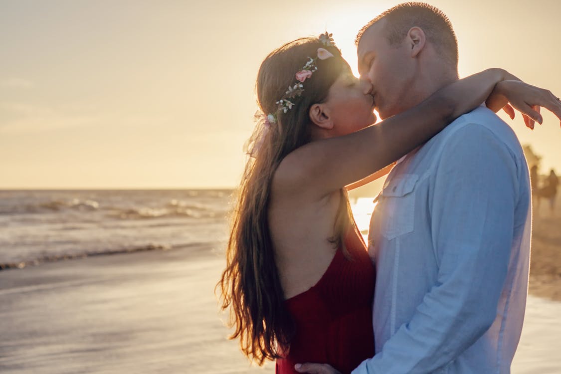 бесплатная Пара, целующаяся на берегу моря Стоковое фото