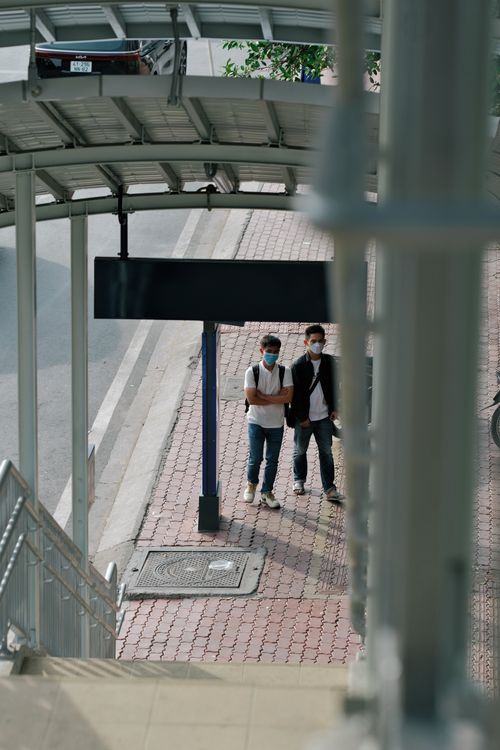 Free Two men with masks waiting at a metro station in Ho Chi Minh City, Vietnam. Stock Photo