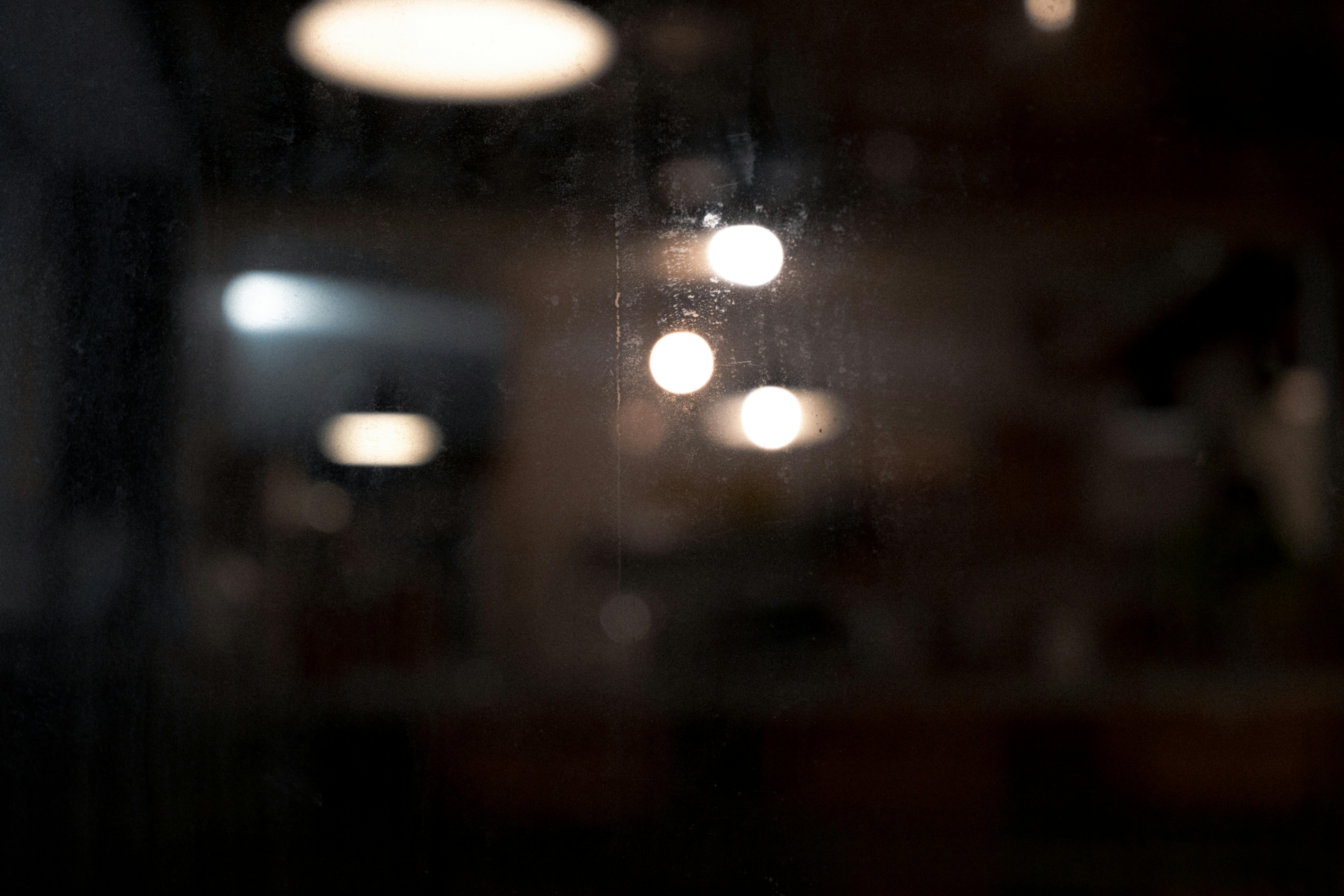 bezplatná Tmavý abstraktní obrázek předvádějící rozmazaná bokeh světla s náladovou atmosférou. Základová fotografie