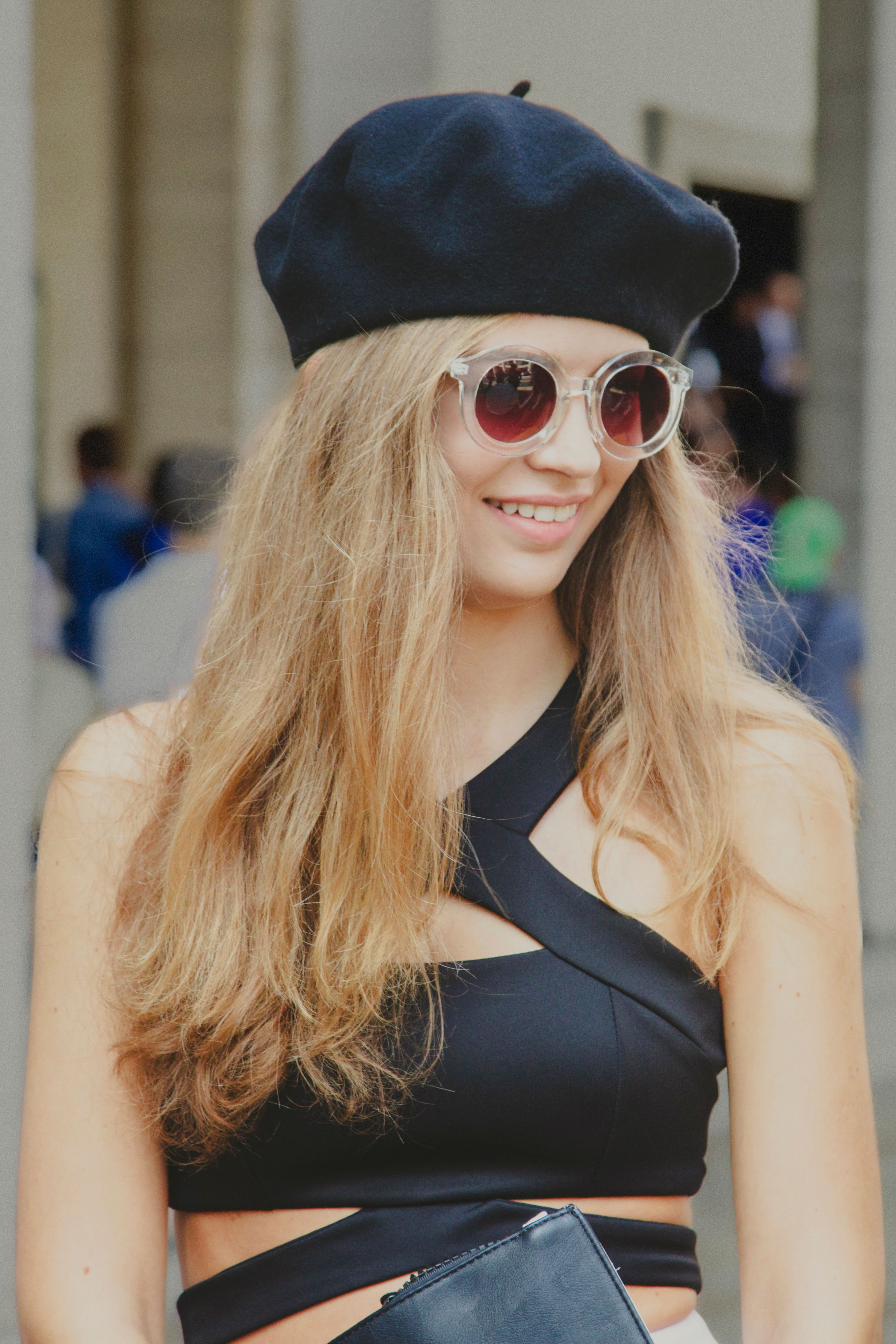 A fashionable model with sunglasses and beret showcases trendy street style in urban setting.