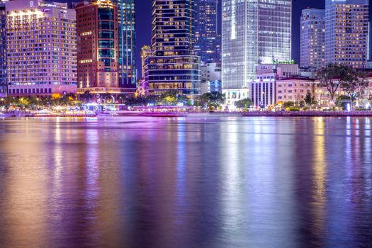 A vivid view of a city skyline reflecting on water at night.