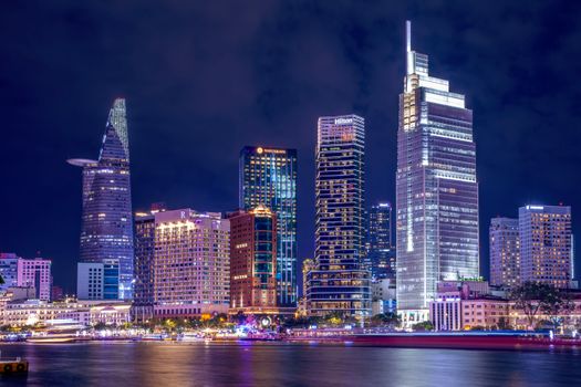 Vibrant night view of Ho Chi Minh City's skyline reflecting on the water, with iconic skyscrapers illuminated.