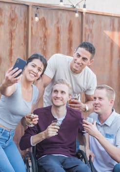 一群朋友在户外自拍，其中包括一位坐在轮椅上的人，大家都很开心