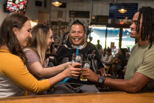 Free A joyful group of friends celebrating and toasting in a vibrant bar setting. Stock Photo