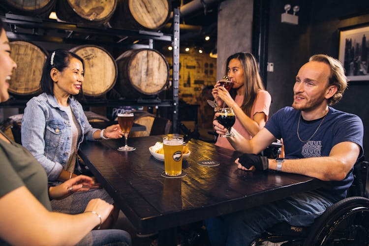 People Seated Around A Table And Drinking Beer