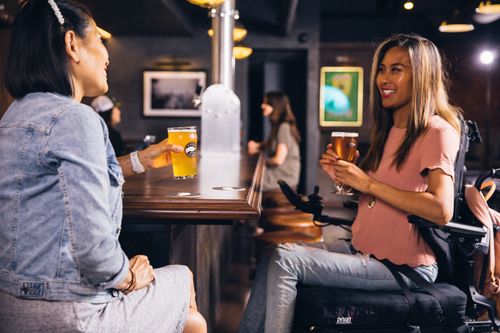 Free Two women enjoying drinks at a bar, smiling and socializing. Stock Photo