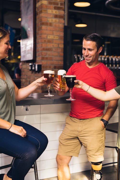 grátis Três Pessoas Brindando Suas Cervejas Em Frente Ao Bar Foto profissional