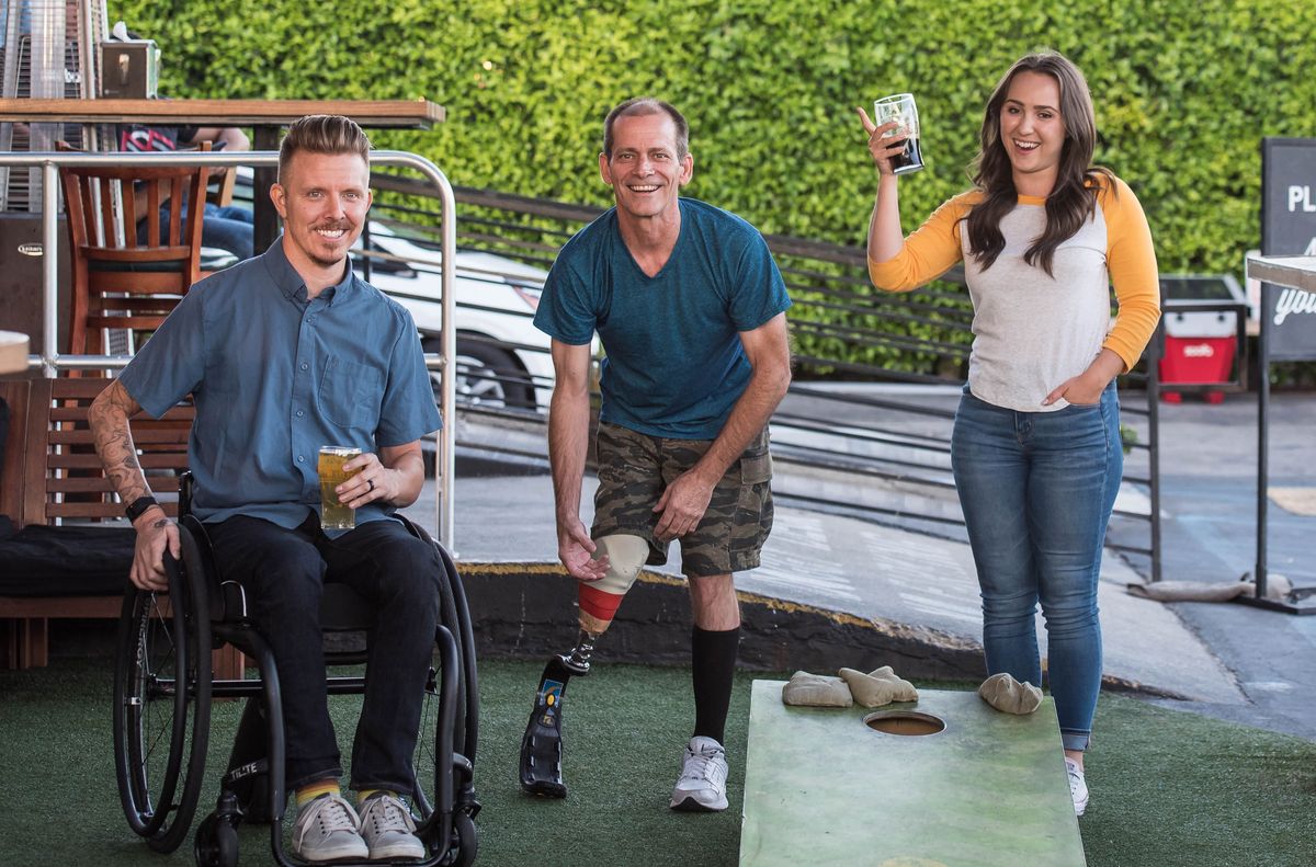 Friends playing cornhole and enjoying drinks at an outdoor game-day gathering