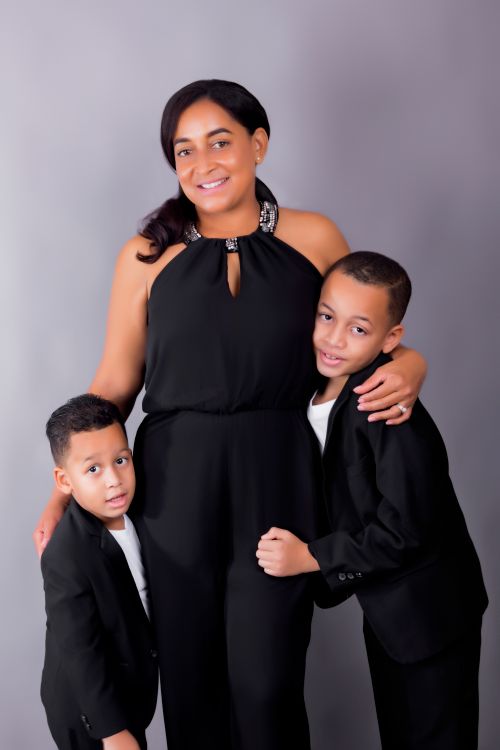 Free Elegant family portrait with mother and two sons wearing black outfits against a gray studio background. Stock Photo