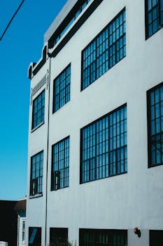 一座高大的建筑物，清澈的蓝天映在大玻璃窗上