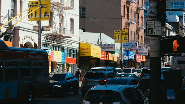 A bustling Chinatown street with heavy traffic, lined with vibrant shops and colorful signs, capturing city life.