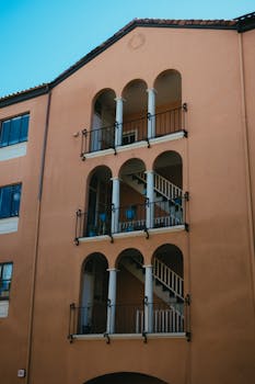 中世纪风格的建筑立面，以拱门、柱子和外部楼梯为特色，融入城市环境之中