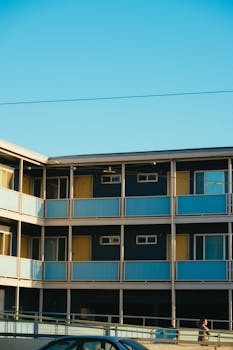 在晴朗的天空下，一栋三层公寓楼采用了蓝黄相间的外观设计