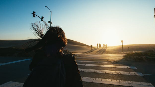 日落时分，一个人穿过沙漠沙丘旁宁静的街道，捕捉到一幅宁静的剪影