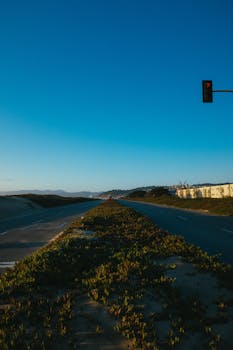 黄昏时分，一条宁静的高速公路上，一个孤独的红绿灯映衬着蔚蓝的天空