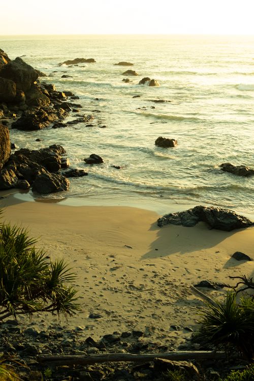 Free Tranquil beach scene at sunrise in Port Macquarie, Australia with rocks and gentle waves. Stock Photo