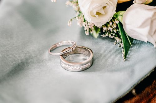 Free Close-up of elegant wedding rings on a soft fabric beside delicate flowers. Perfect for romantic themes. Stock Photo