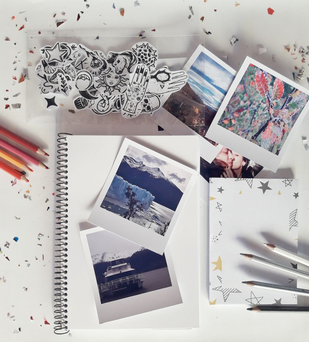 Mesa creativa con fotografias, cuaderno y material de papeleria