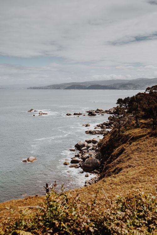 Free Breathtaking view of a rocky coastline with cliffs and ocean under a cloudy sky. Stock Photo