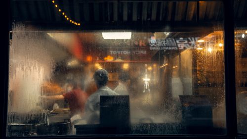 Free Candid street view of a bustling New York kitchen through a moody, wet window scene. Stock Photo