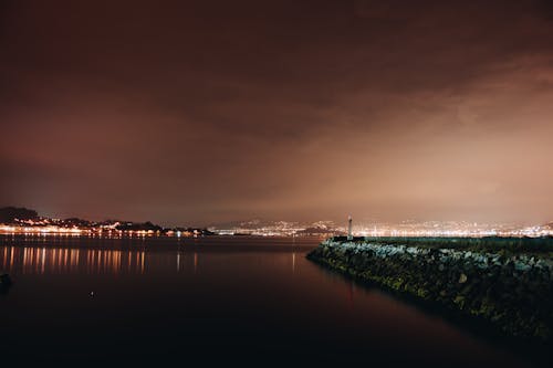 бесплатная Водоем вдоль города в ночное время Стоковое фото