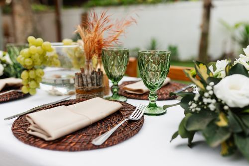 Free Outdoor table setting with green glassware, grapes, and floral decor. Elegant and inviting atmosphere. Stock Photo