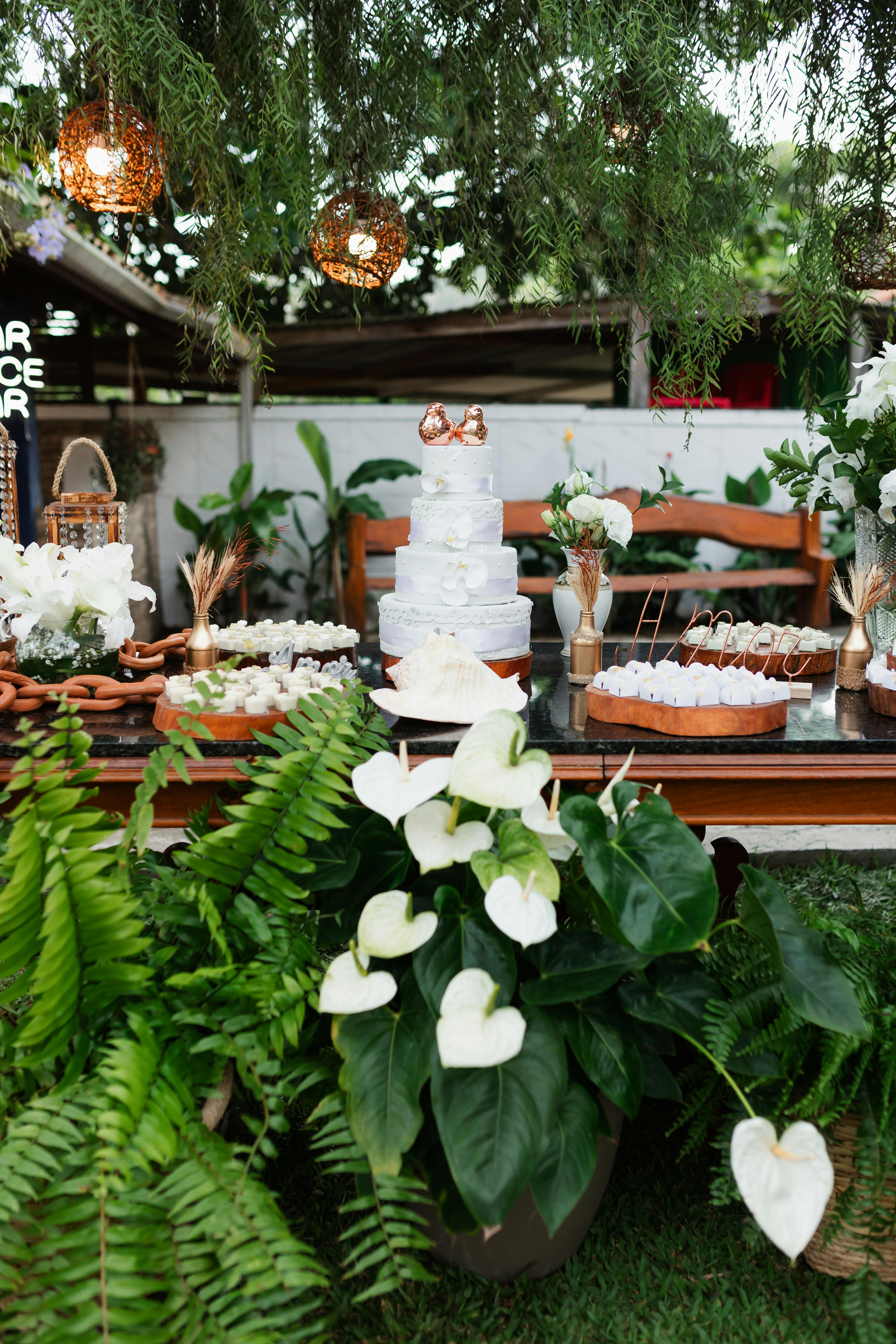 A garden party table with 4 tier cake and cupcakes on it
