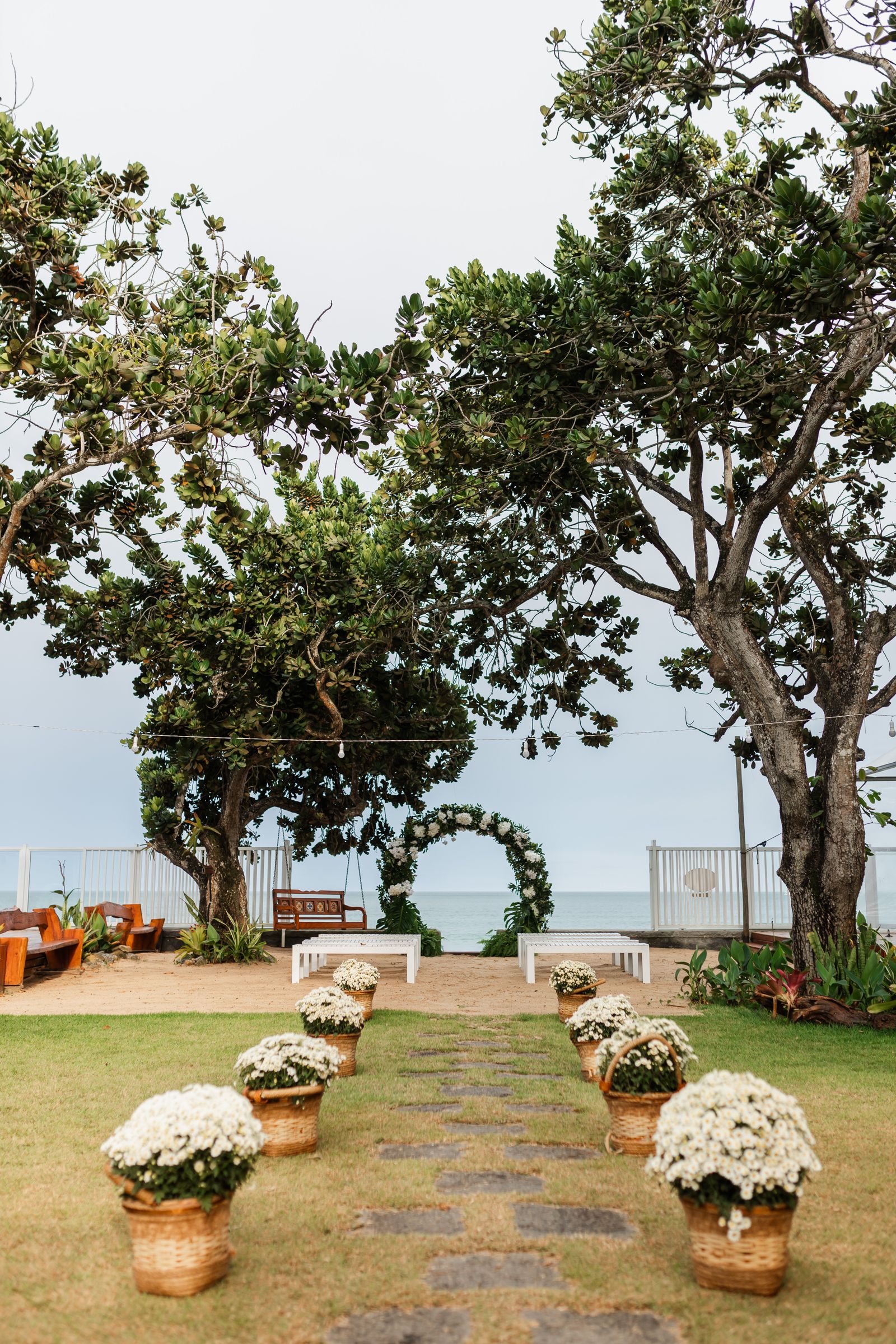 Light-toned wedding ceremony setup with floral aisle details near the coast.