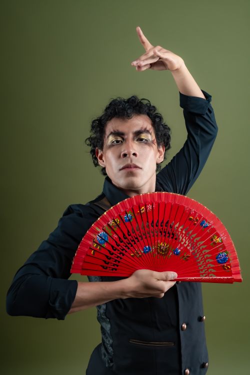 Free A male flamenco dancer poses gracefully with a red fan in a studio setting. Stock Photo