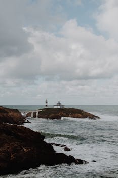 岩石岛屿上被海浪和云层包围的灯塔风景