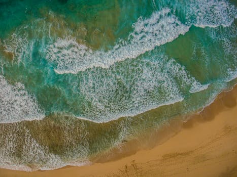 Vibrant aerial view of waves crashing on the sandy shores of Rincón beach in Puerto Rico.