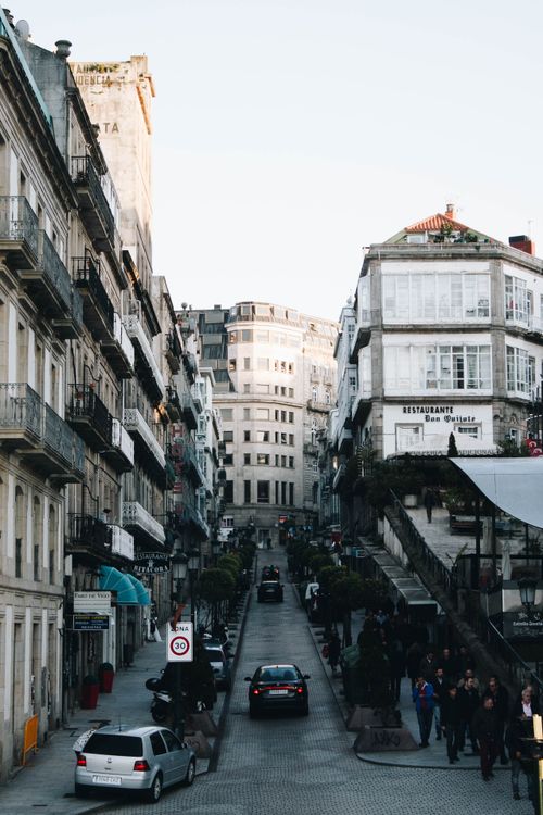 Free Quaint European street scene showcasing architecture, bustling with people, cars, and vibrant urban life. Stock Photo