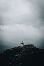 一座孤独的灯塔矗立在岩石山上，上方乌云密布，营造出一种阴郁而富有氛围的场景