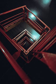 俯视昏暗环境中带有红色栏杆的螺旋楼梯