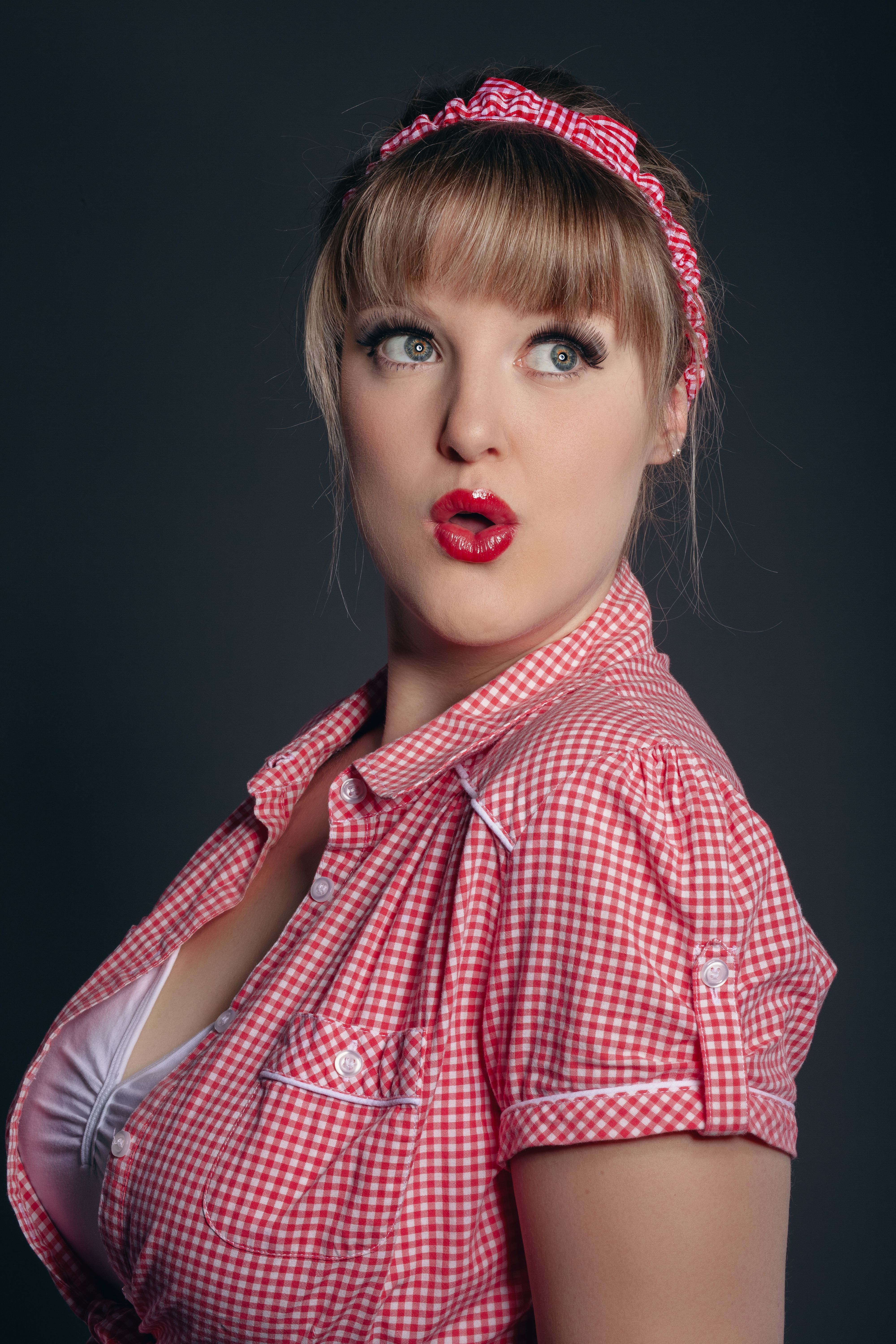 Chic portrait of a woman in retro attire, red lipstick, and gingham shirt.