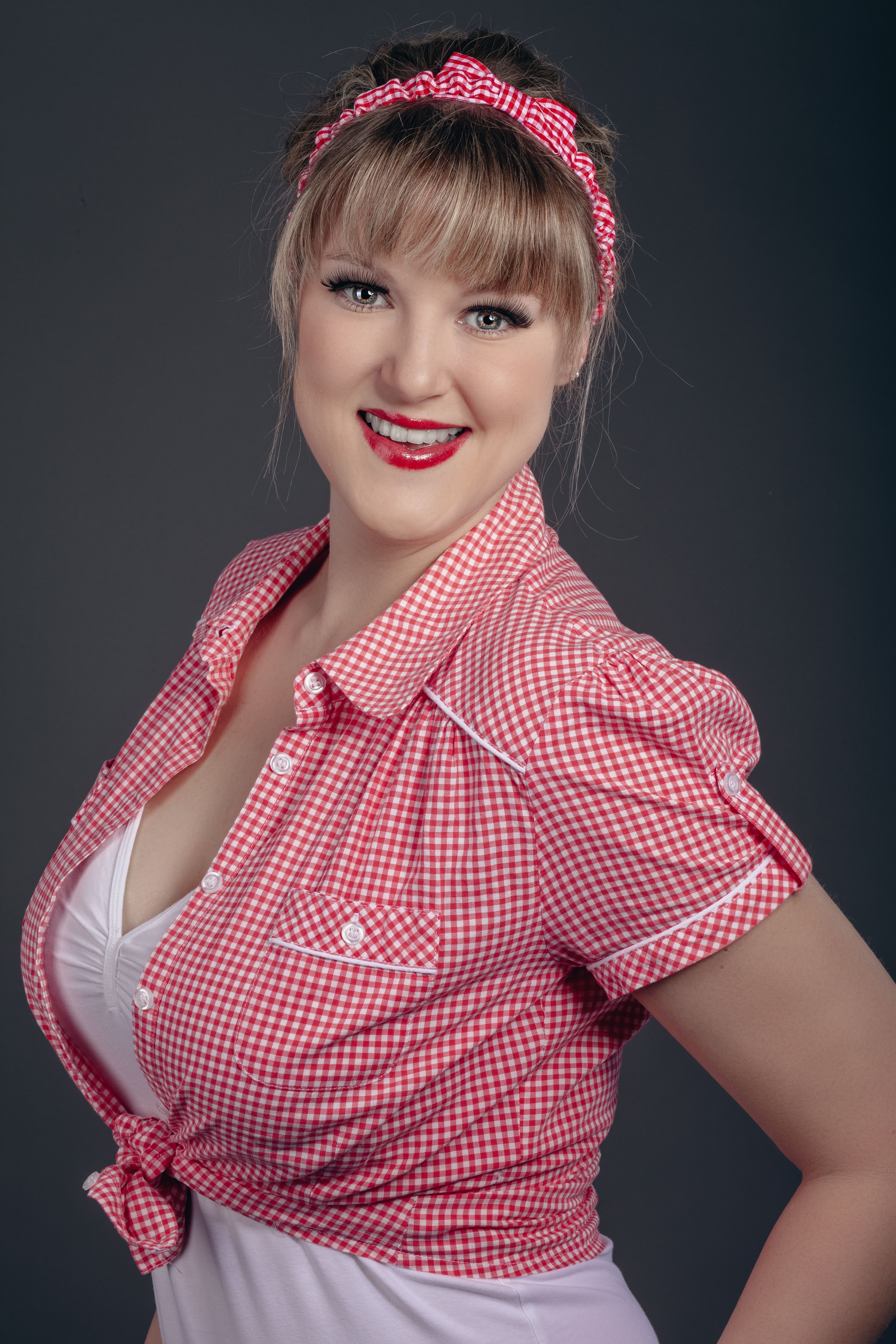 Cheerful woman in red checkered shirt and headband, vintage style portrait.
