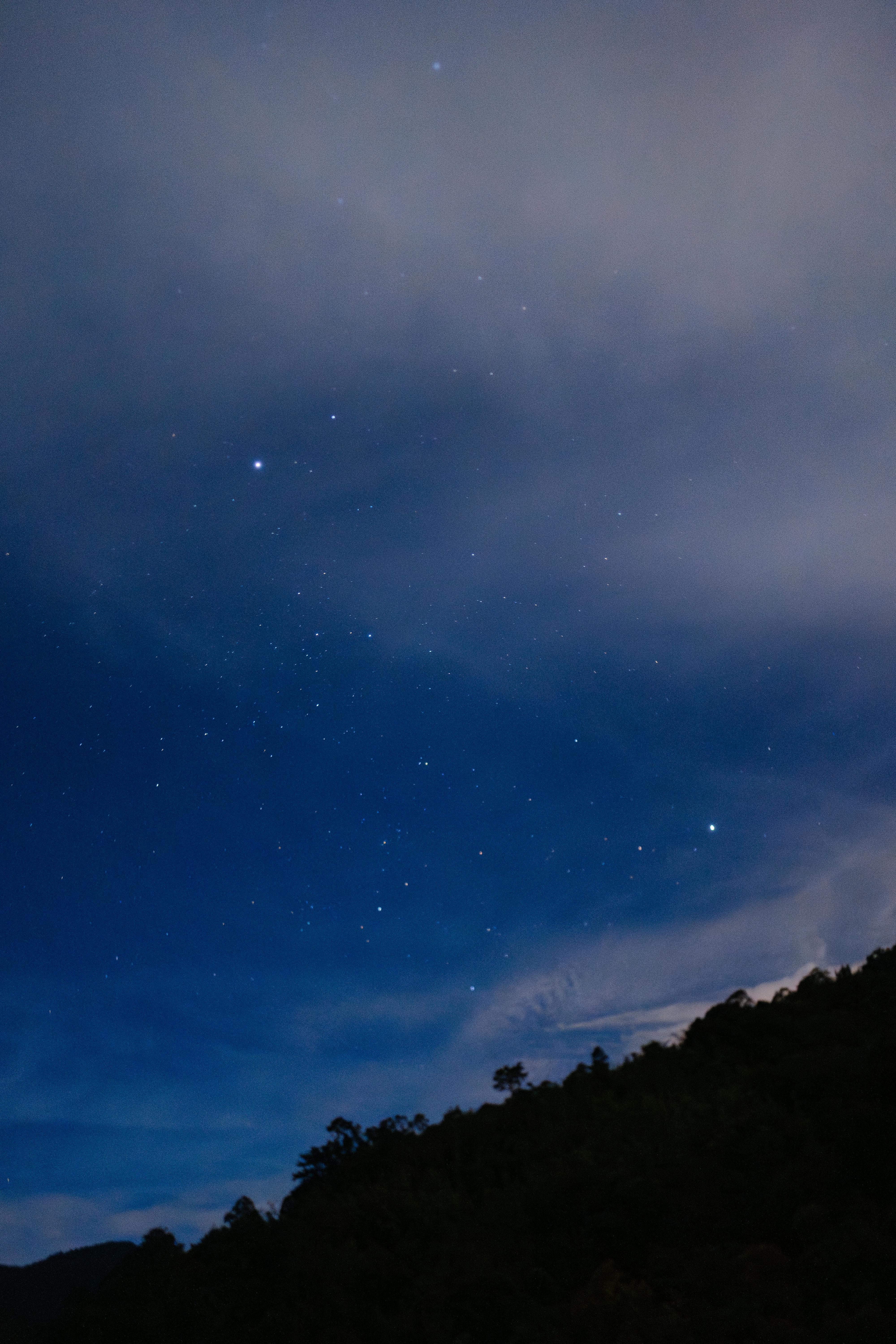 A serene view of a starry night sky with clouds over a Malaysian landscape.