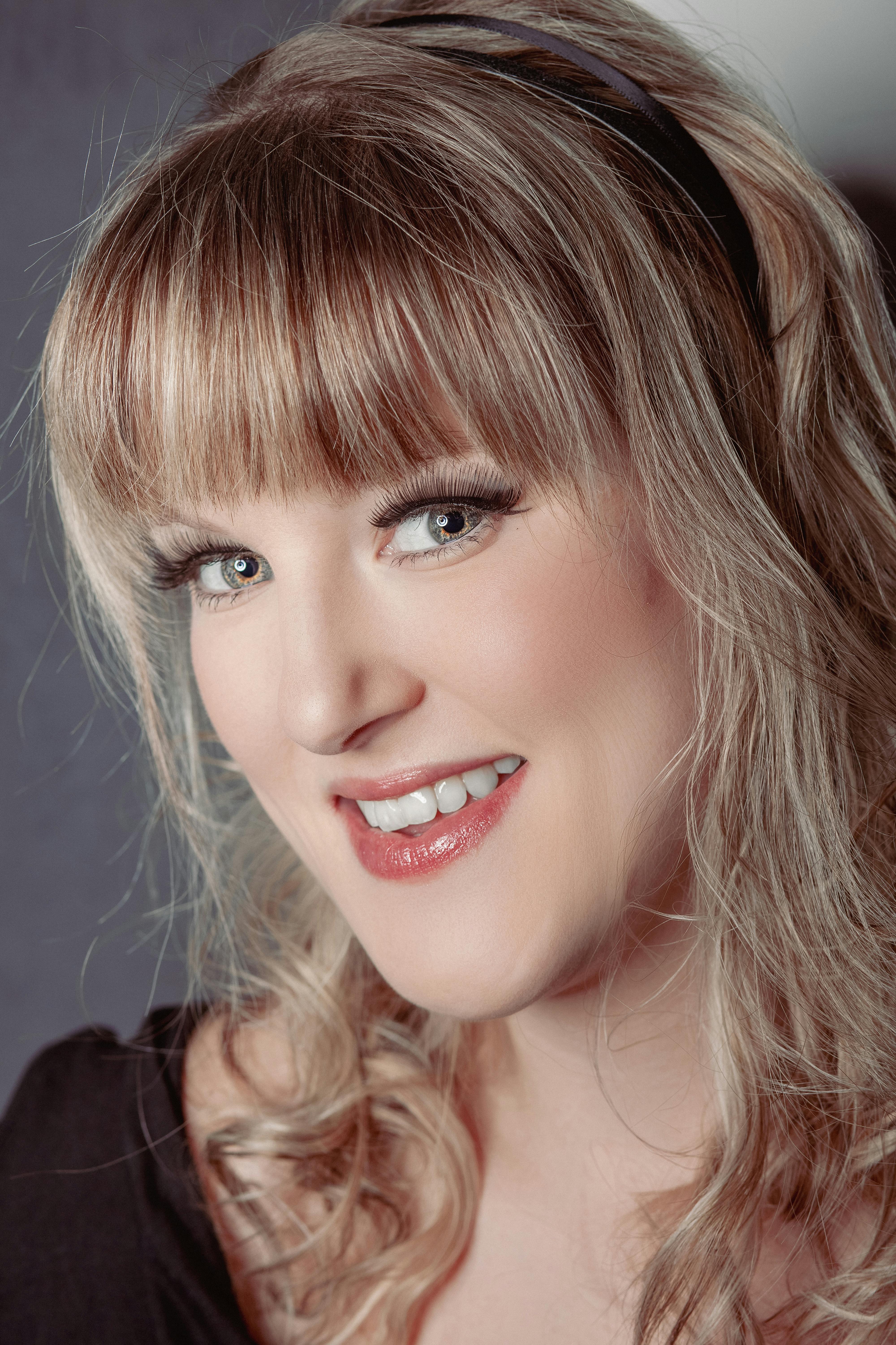 Close-up portrait of a smiling woman with blonde hair and bangs.