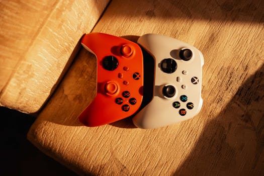 Two gaming controllers on a wooden surface illuminated by warm sunlight, ideal for gaming themes.