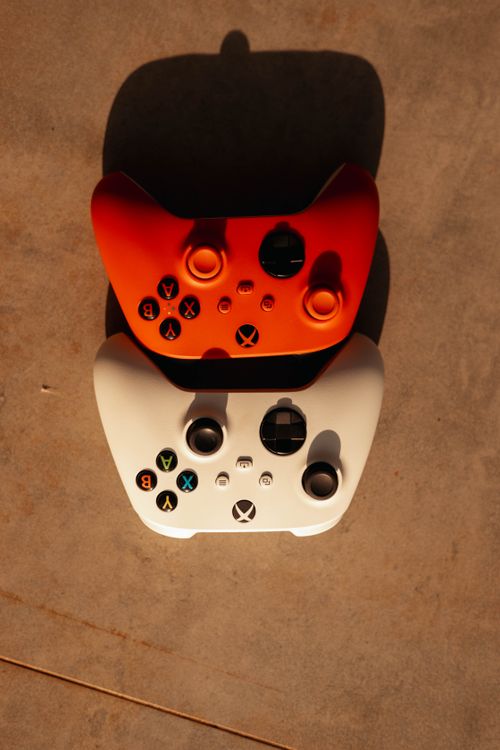 Free Top-down view of two vibrant game controllers casting shadows on a surface. Stock Photo
