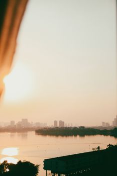 Serene sunrise over a tranquil lake with a city skyline in the background, creating a peaceful mood.