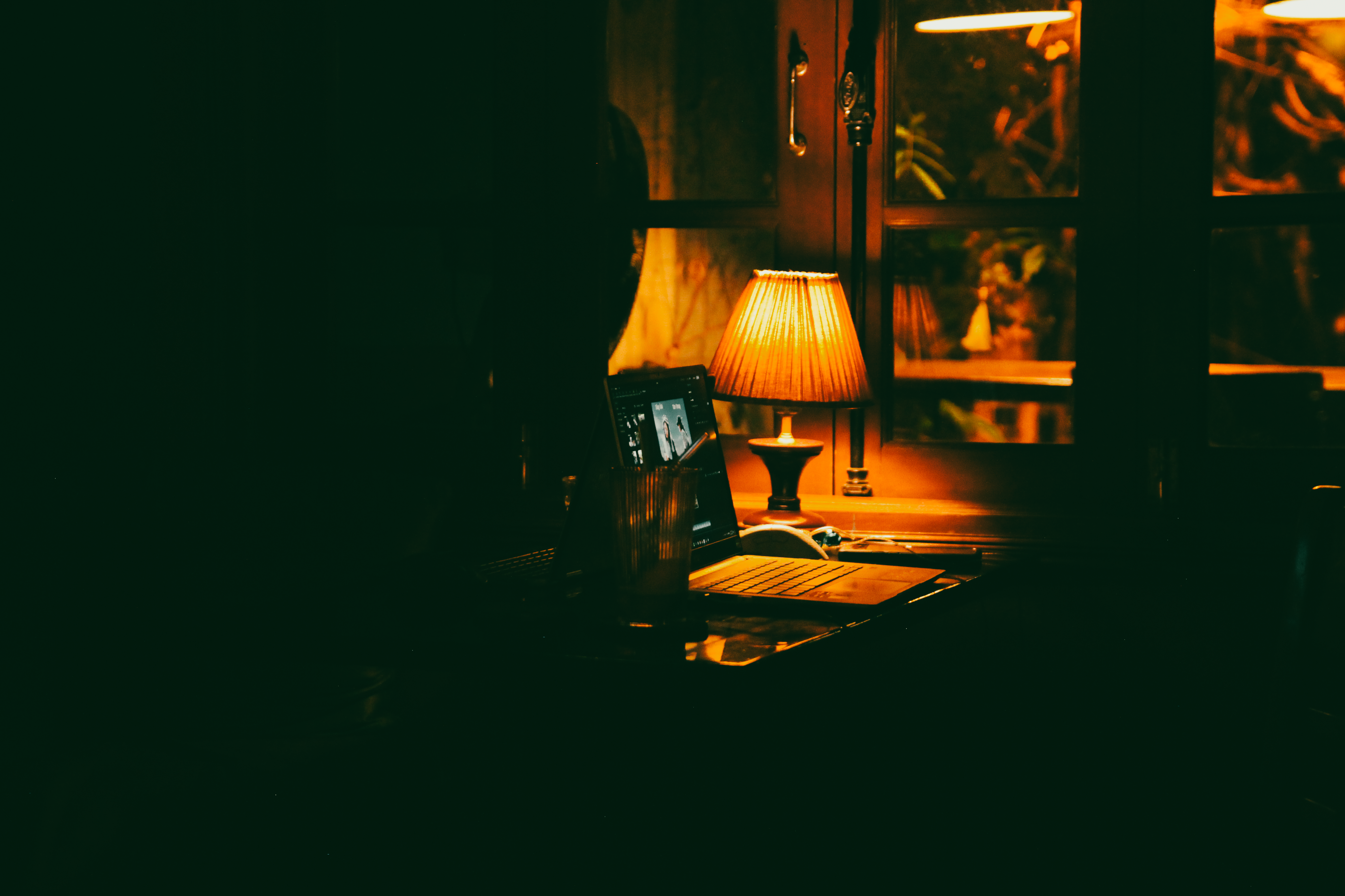 Free A warm and inviting night workspace illuminated by a vintage lamp, perfect for late-night work sessions. Stock Photo