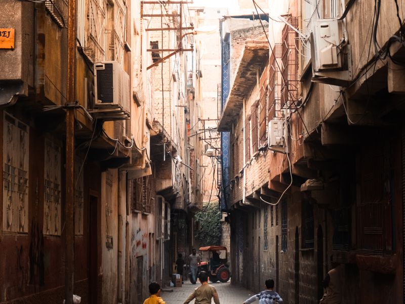 Kids running through narrow urban alley with rustic buildings - school district licensing